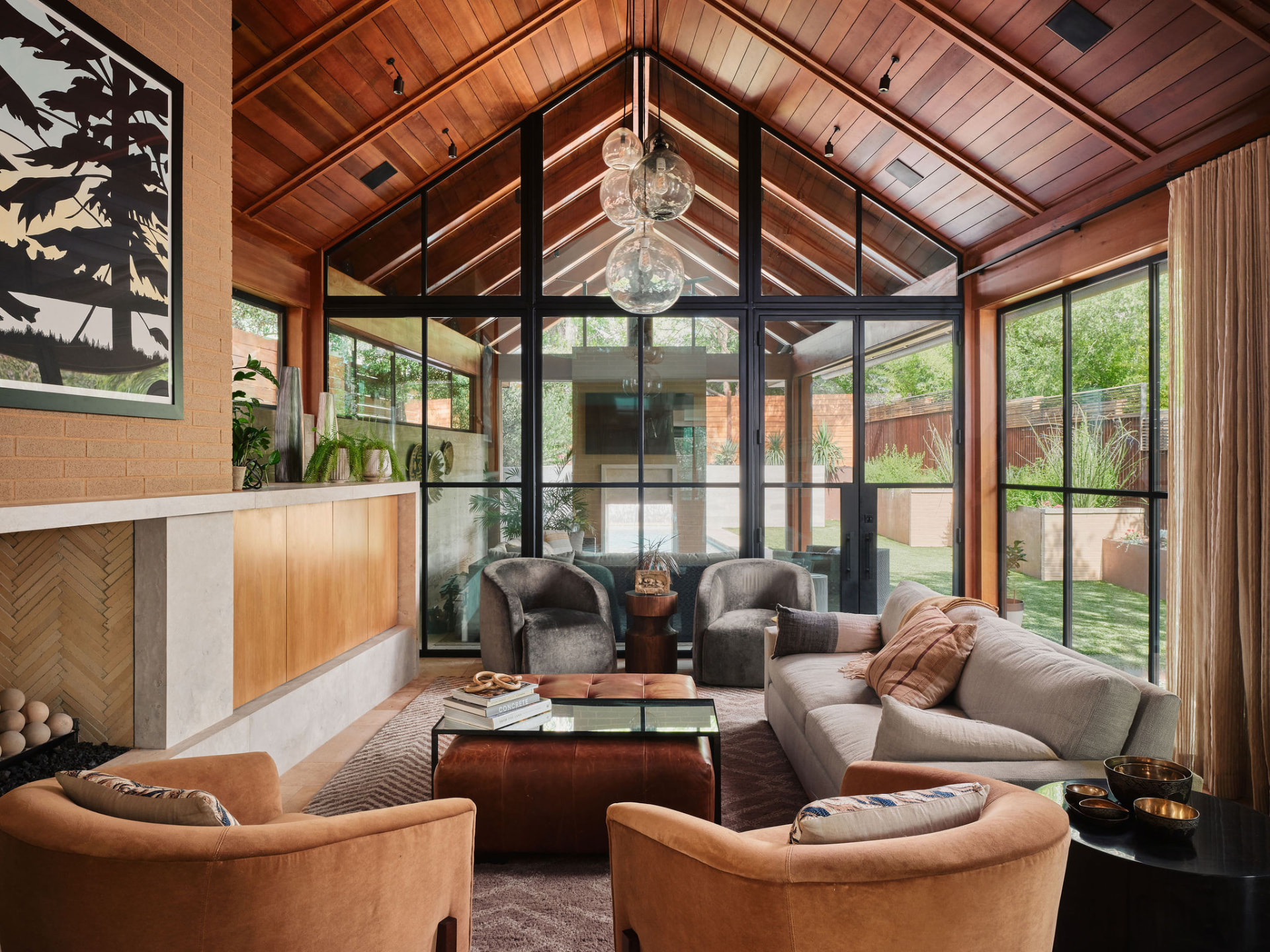 Austin living room with vaulted wood ceiling and floor-to-ceiling steel windows overlooking a pool and yard