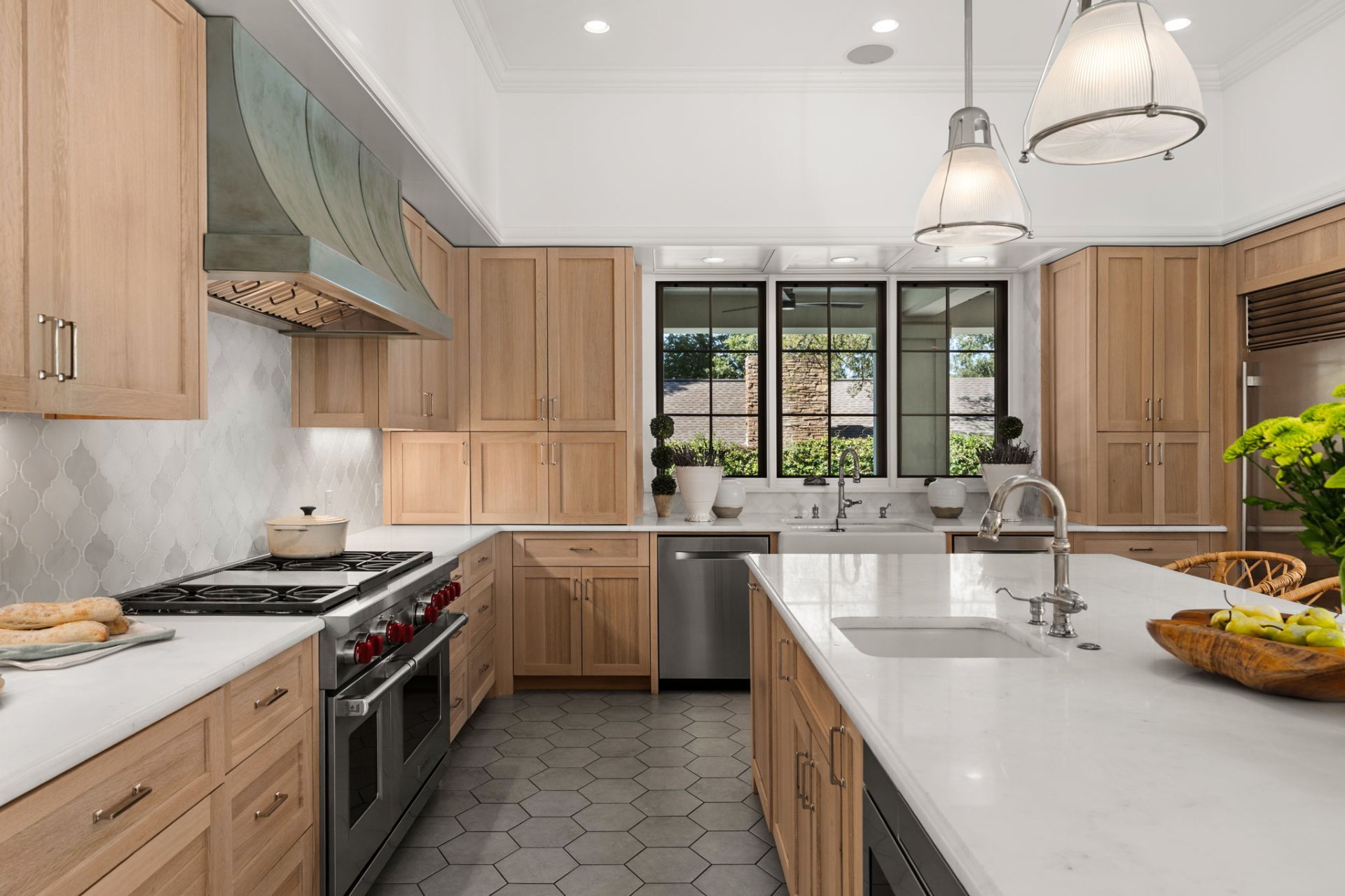 Light wood cabinetry, marble countertops, and a copper range hood in a refined Austin luxury kitchen, illustrating the construction and design quality defining the current high-end market