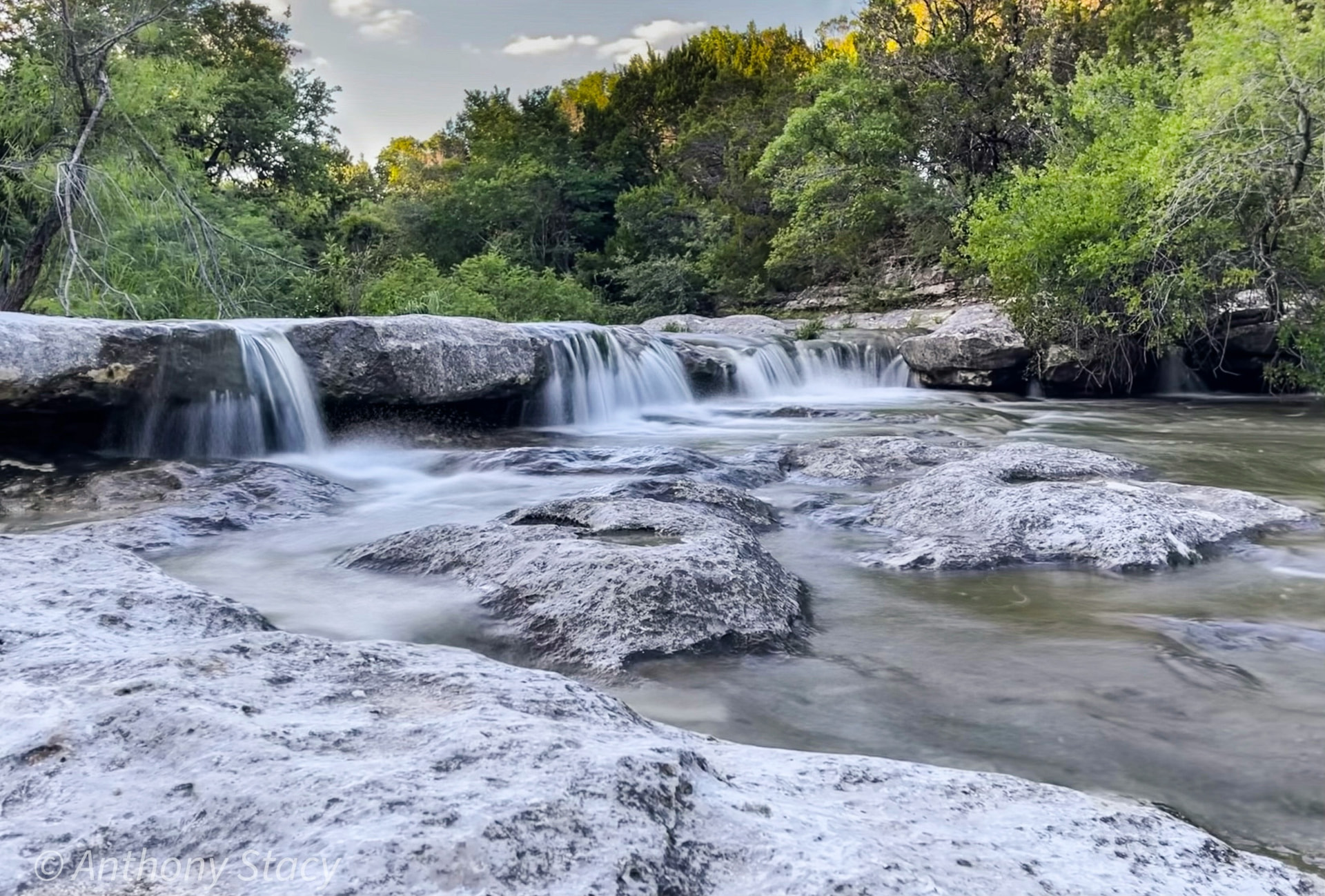 Austin Hiking Trails, Greenbelts and Parks: The 2026 Guide (and What a Greenbelt Lot Is Really Worth) Barton Creek Greenbelt limestone ledges and cascading waterfalls framed by Hill Country trees in Austin