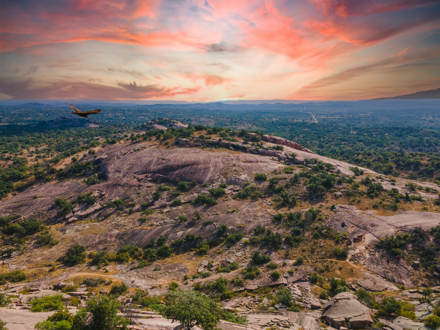 Aerial view of Texas Hill Country ranch land at sunset with golden light across rolling pastures and winding trails
