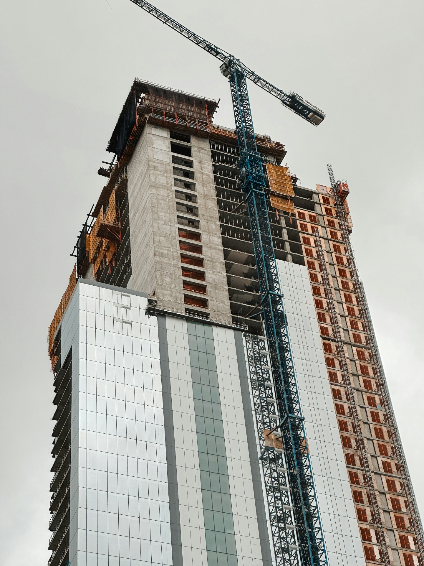 High-rise commercial tower under construction in Austin with cranes and scaffolding, illustrating active commercial land development