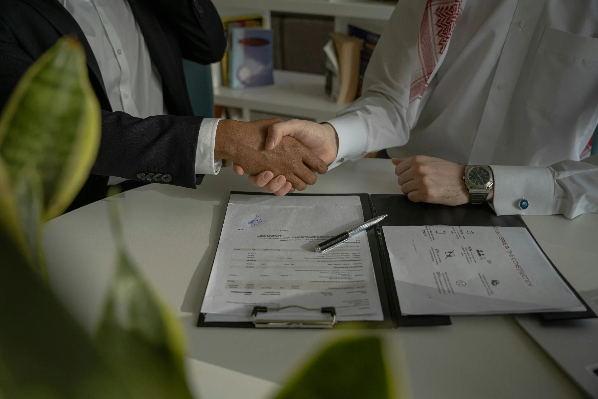 How Intermediary Works in Texas Real Estate: What Buyers and Sellers Need to Know Two parties shaking hands over a signed real estate contract with pen on clipboard, representing an intermediary transaction in Texas