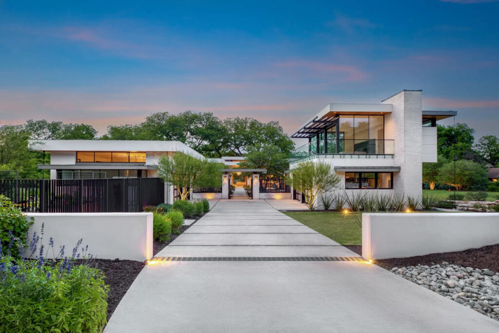 Modern luxury Austin estate at twilight with illuminated driveway, glass facade, and landscaped courtyard, representing the kind of off-market home that trades privately in West Lake Hills and Barton Creek